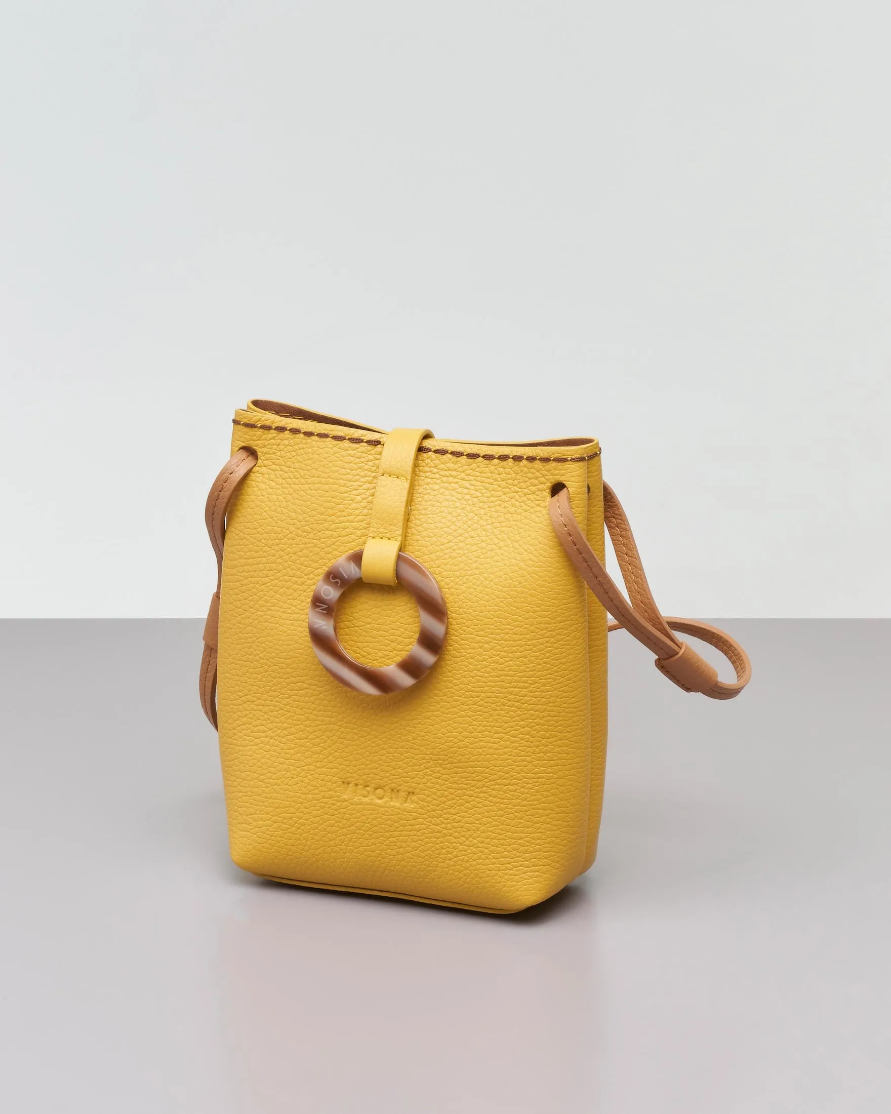 Mini bag in pelle martellata gialla con tracolla color cuoio e chiusura ad anello in osso